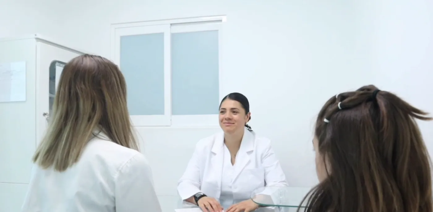 Doctora en consulta con dos pacientes